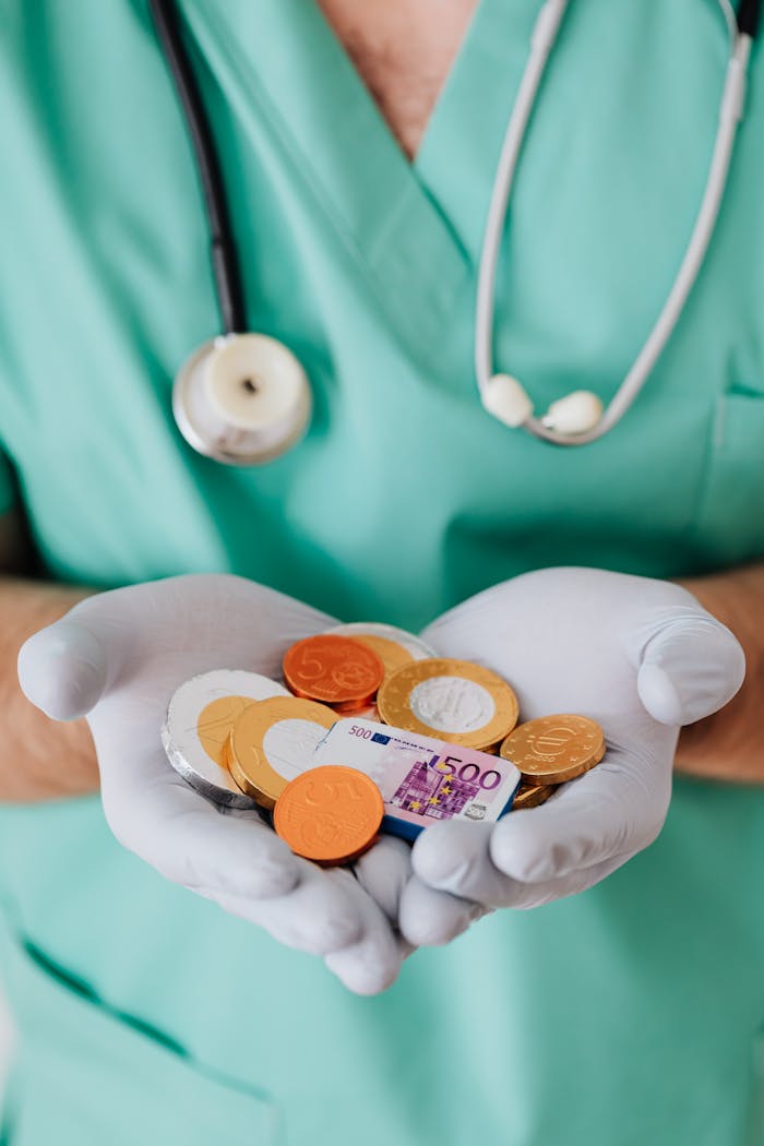 About From above crop faceless doctor with stethoscope on shoulders holding in hands chocolate coins